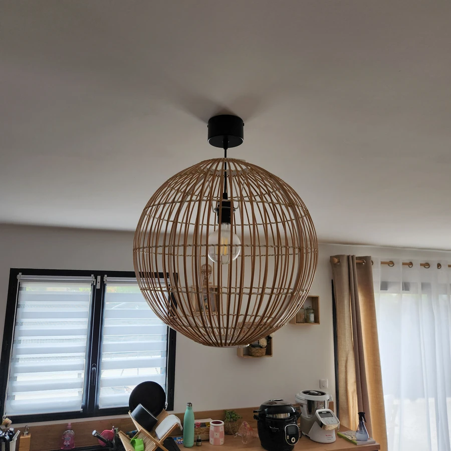 Suspension luminaire sphérique en rotin naturel suspendue au plafond blanc d'une cuisine moderne