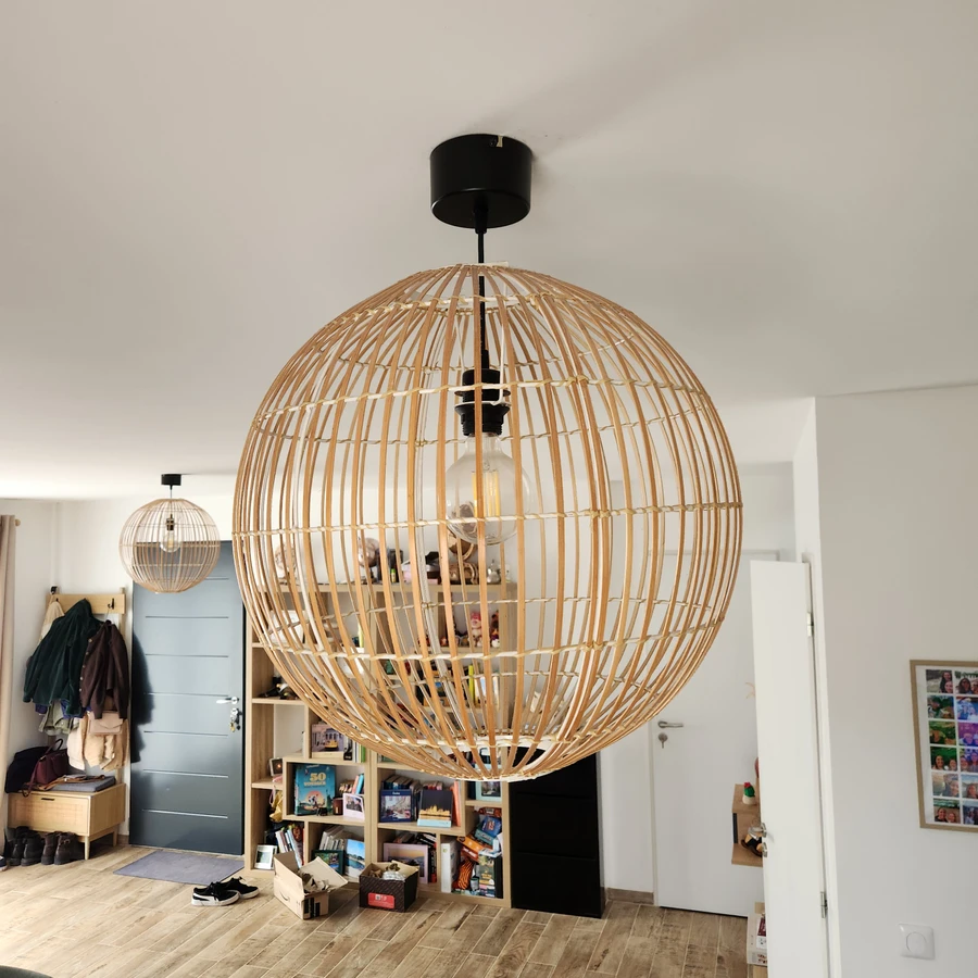 Grand lustre suspendu en bois naturel de forme sphérique dans un intérieur moderne avec étagères et mobilier